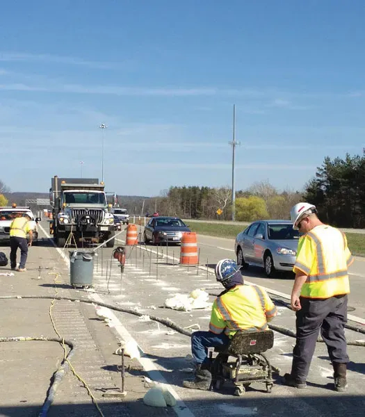 Two URETEK technicians at work with more crewmembers and trucks in background