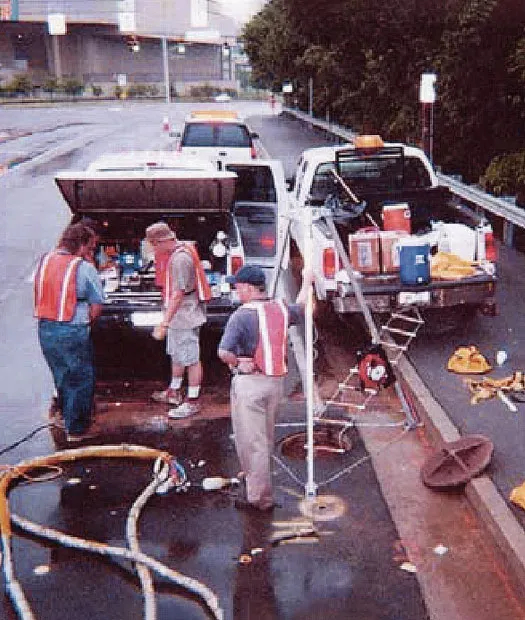Several URETEK technicians at work on wet asphalt
