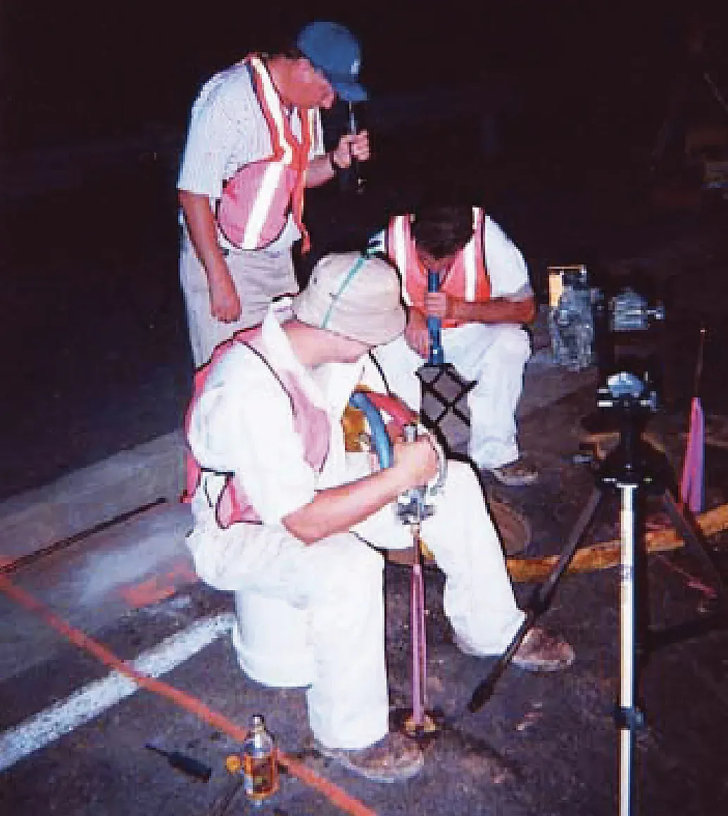 Three URETEK technicians analyze roadway at night