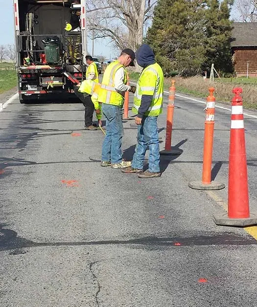 Three URETEK technicians on roadway blocked off by traffic cones