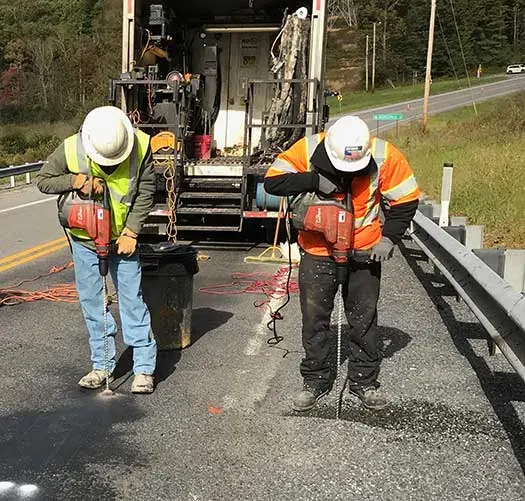 URETEK technicians drill holes with large truck in background