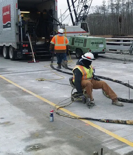 URETEK technician works in foreground as another inspects truck in background