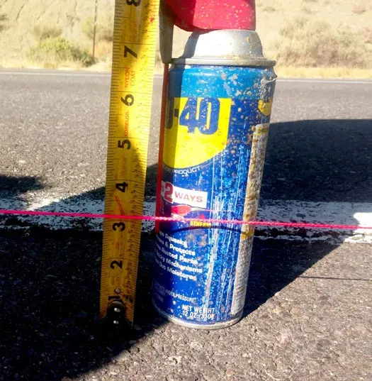 WD 40 with a tape measure next to it that's 8 inches tall