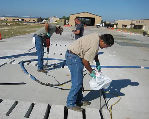 Three technicians performing URETEK Deep Injection on airforce runway