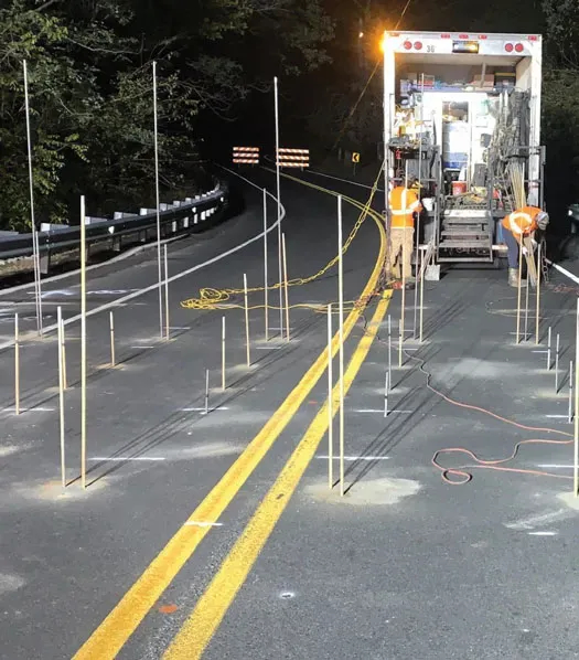 URETEK technicians preparing tubing on roadway at night